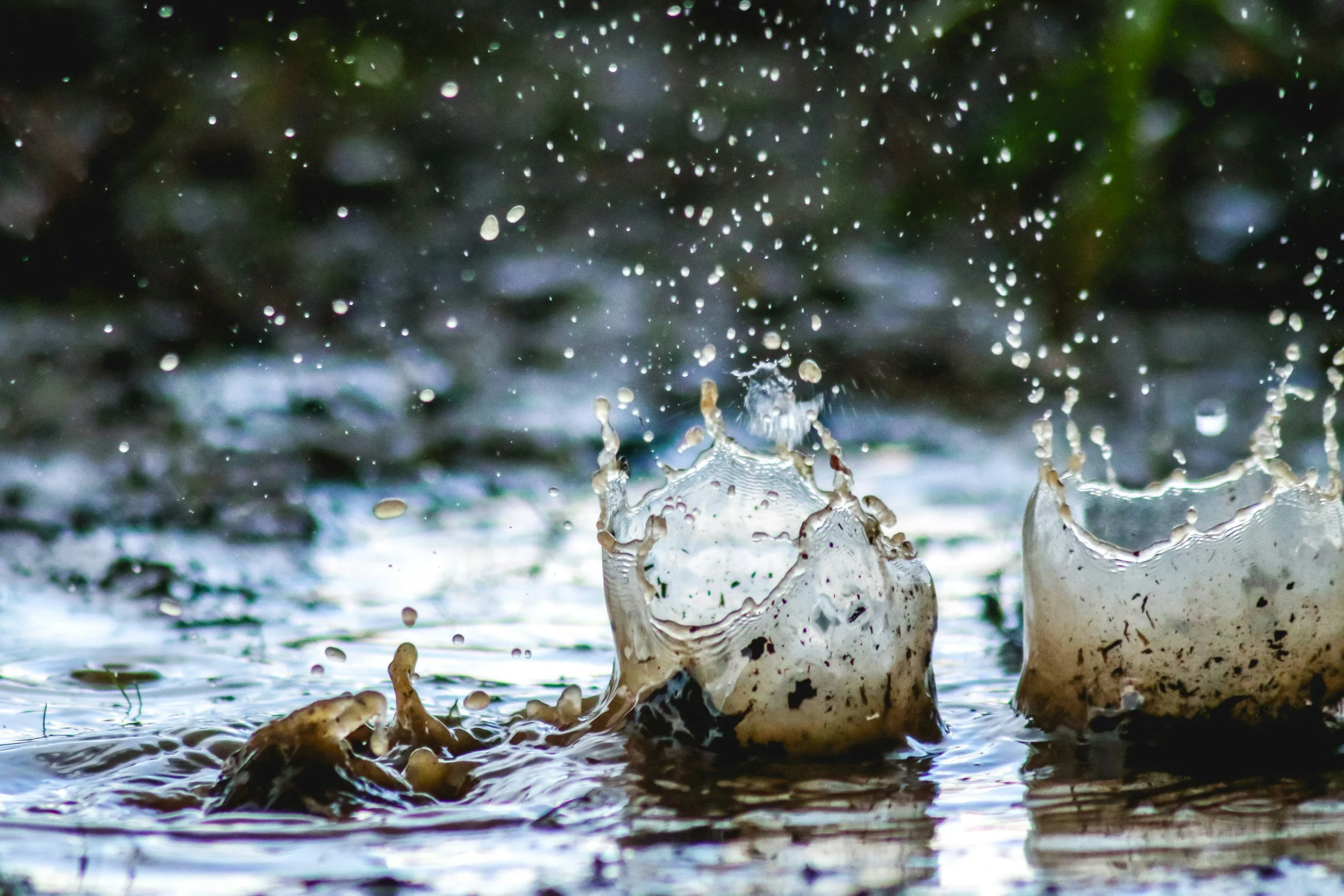 Close-up of water splashing and droplets flying in the air as a stone hits the surface of a pond or river.