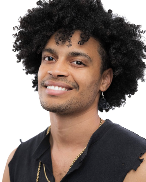 A smiling man with curly black hair, wearing a sleeveless black shirt and earring, against a white background.