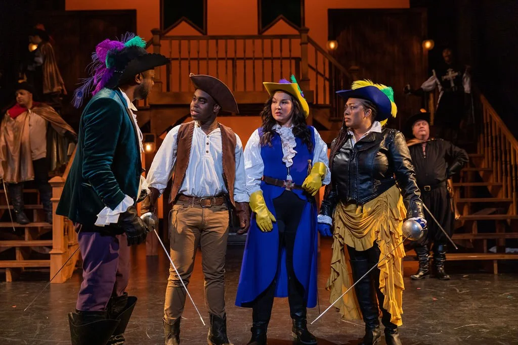 Actors dressed as musketeers on stage in a theatrical production.