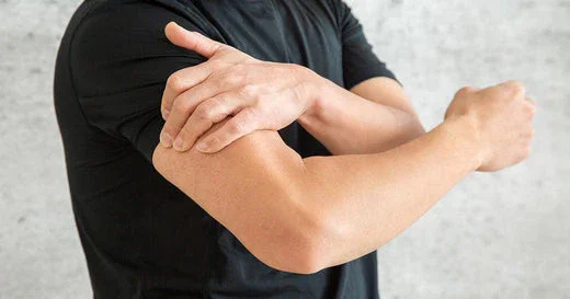A person wearing a black shirt showing a flexed arm with their other hand resting on it