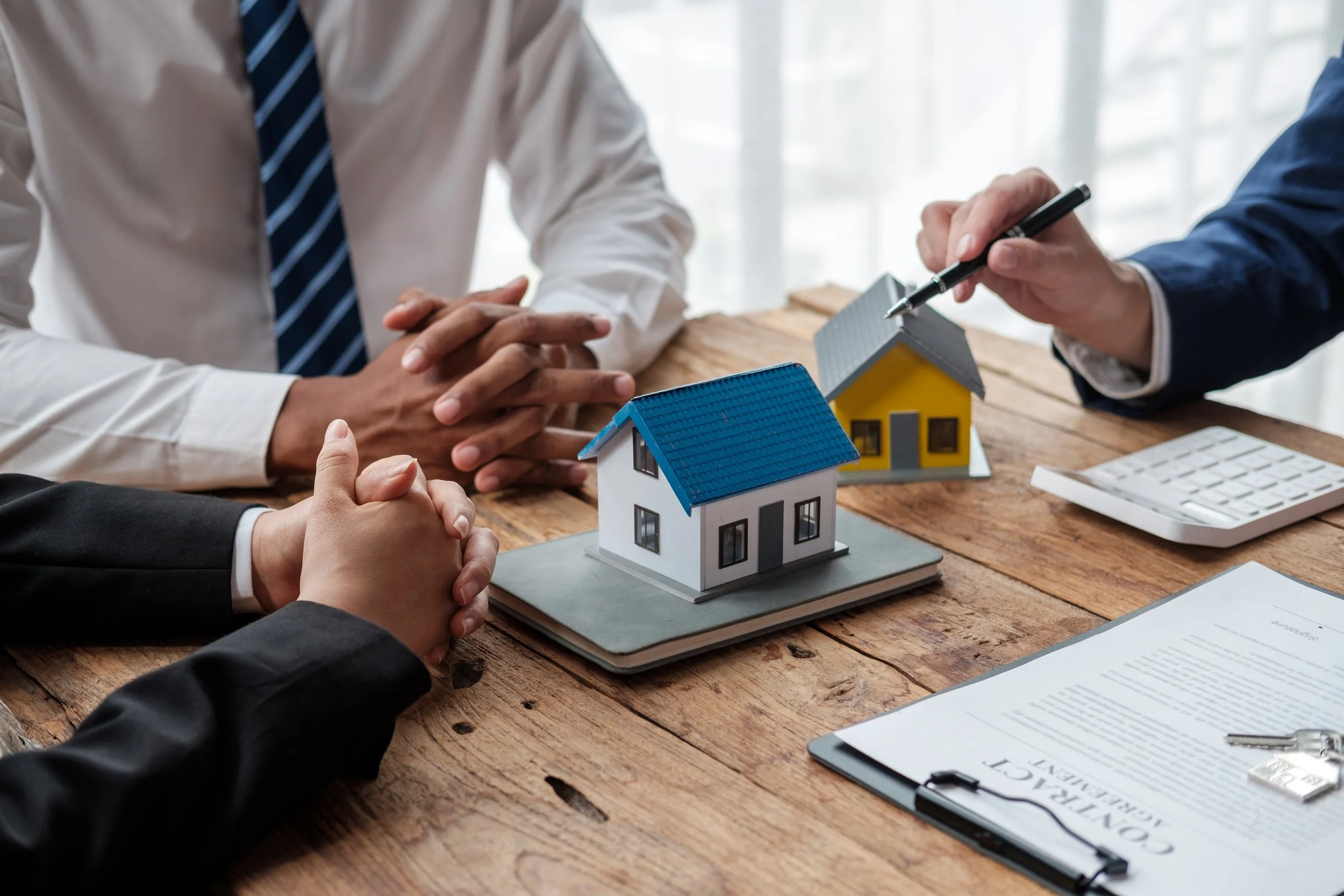 Real estate agent showing two model houses to clients during a meeting.