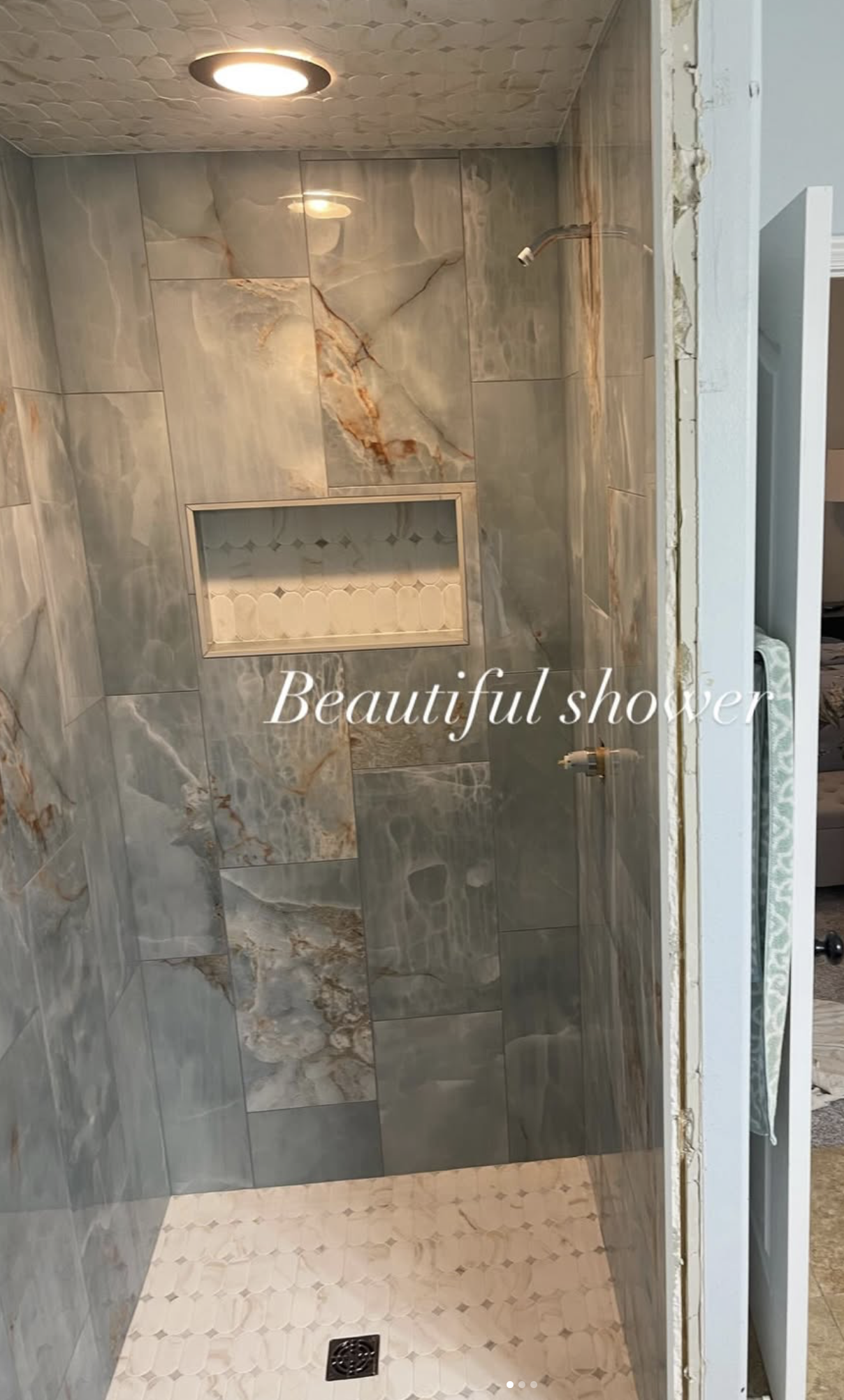 A marble-tiled shower with built-in shelf and two unfinished shower heads, with the caption "Beautiful shower."