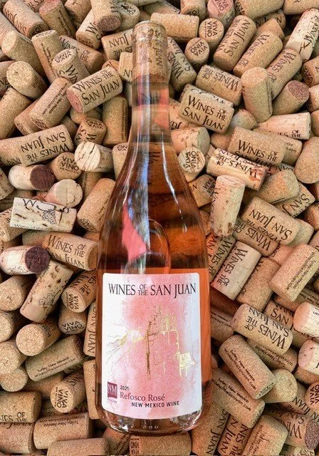 A bottle of Wines of the San Juan Reposco Rosé wine on top of numerous wine corks, with some displaying the winery name and logo.