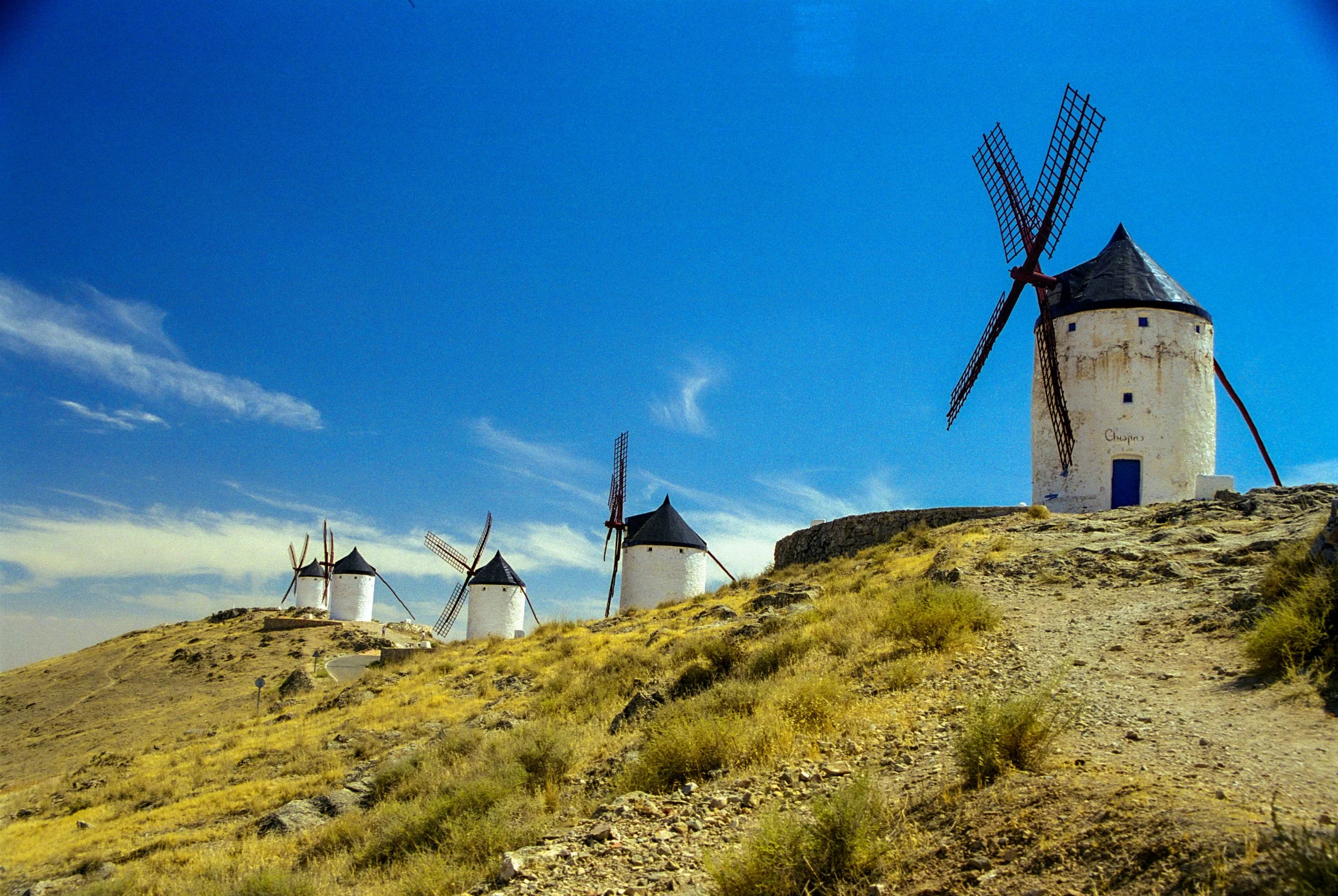 Landscape with traditional Spanish windmills under a blue sky.