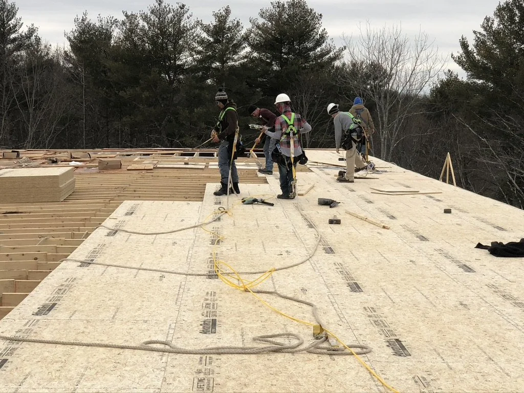 Construction workers installing or working on a roof, with wooden framing and underlayment, 