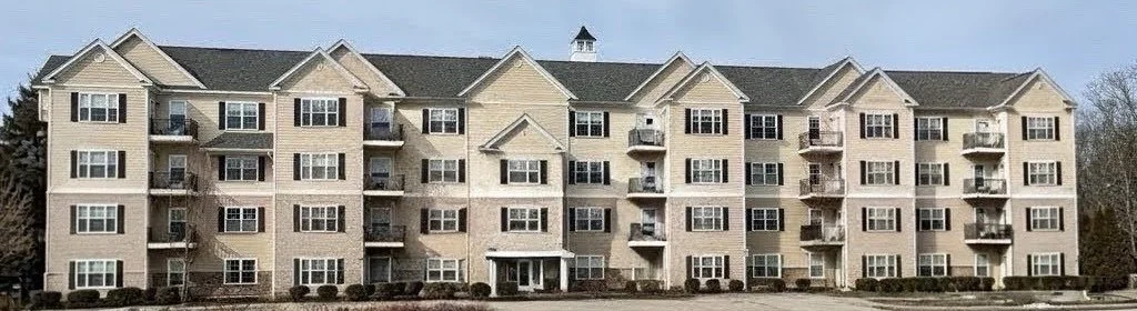Multi-story beige apartment building with balconies and a gabled roof