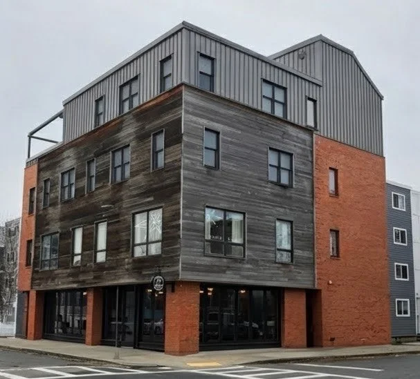 Multi-story building with brick, wood, and metal exterior, large windows, and a corner entrance.