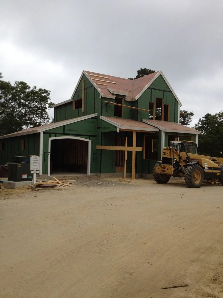 A house under construction with green sheathing, missing some roofing