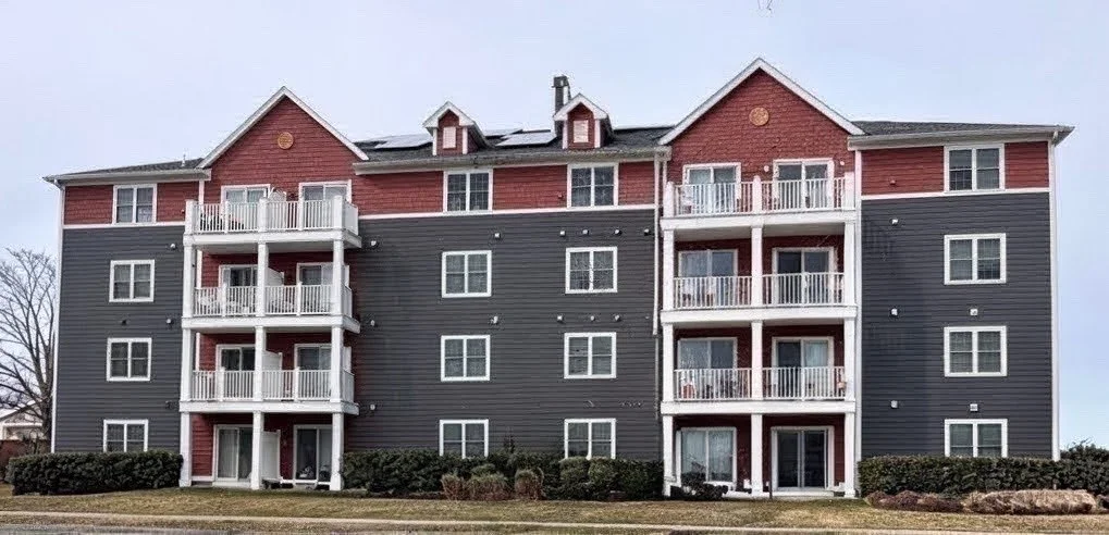 Four-story apartment building with red and black exterior, featuring multiple balconies and white railing
