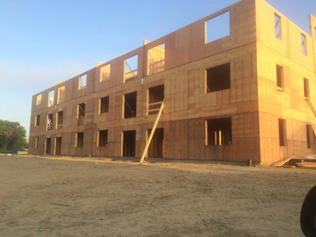 A multi-story building under construction with wooden framing and multiple window openings, 