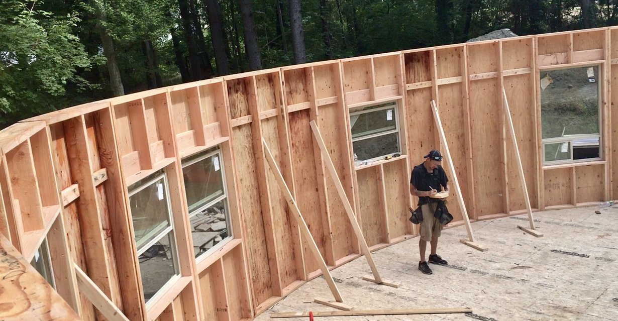  wooden floor inside a building frame with unfinished walls, windows, and support braces.