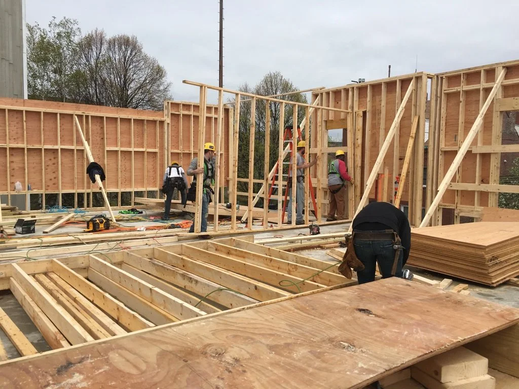 Construction workers assembling wooden framing for a building at a construction site.