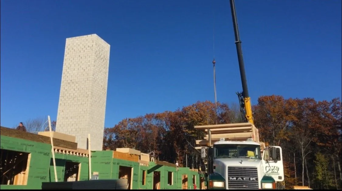 Construction site with a crane lifting materials, partially built wooden structure, green insulation, 