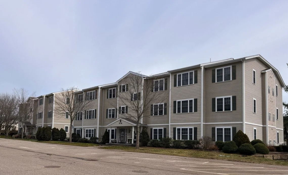Exterior of a beige multi-story apartment building with black shutters