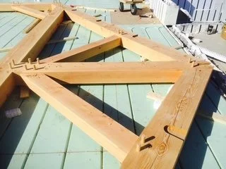 Construction framing with wooden beams on a green rooftop surface.