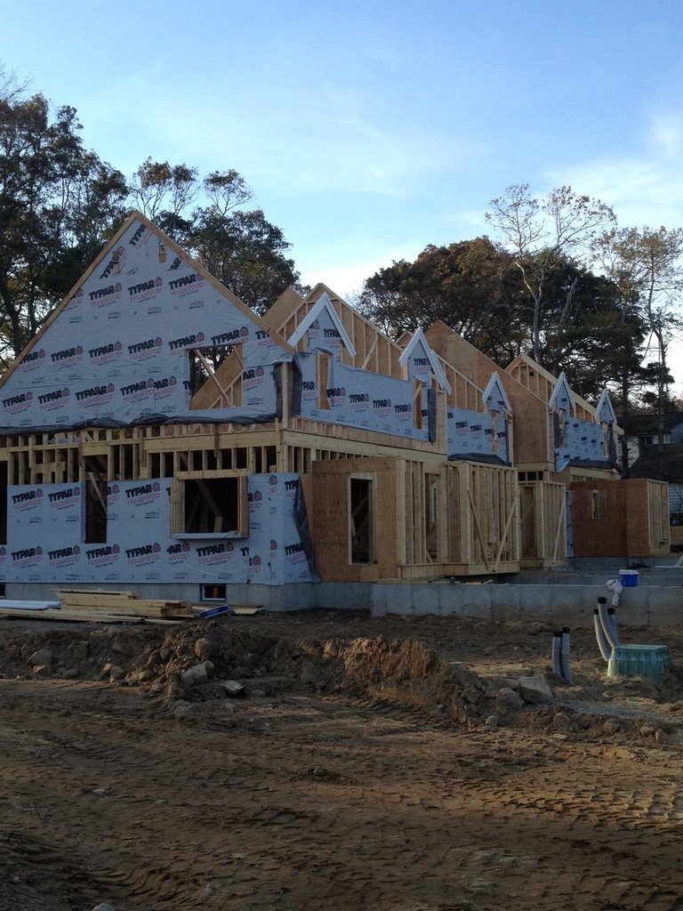Construction site of a new house with wooden framing, multiple gable roofs, and some windows installed