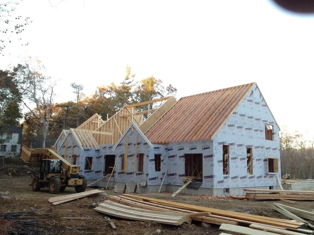 Construction site with a house under construction and a forklift on the left side.
