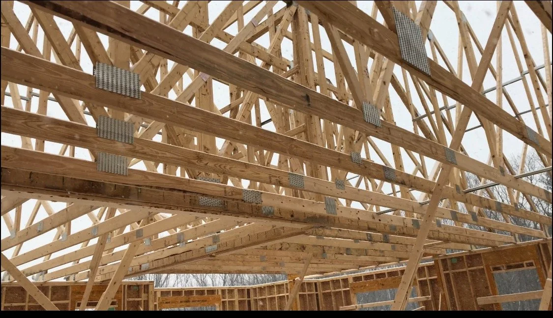 Construction of a wooden building frame with scaffolding and steel plates for support.
