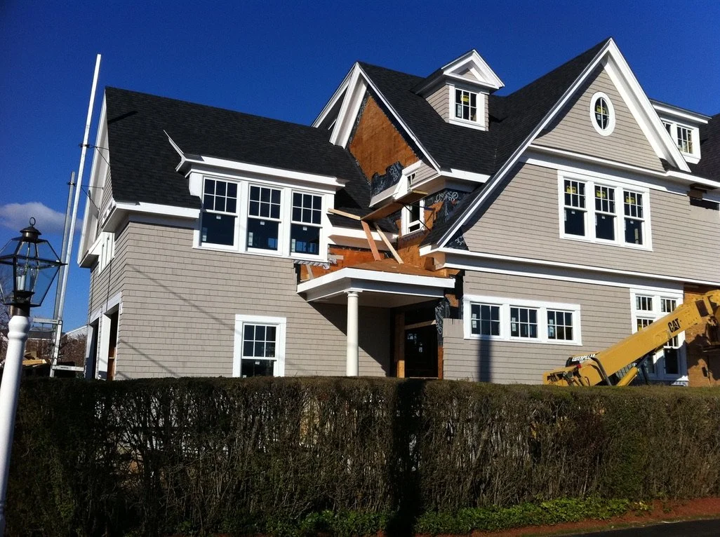 A multi-story house undergoing renovation with exposed wooden framework, construction equipment