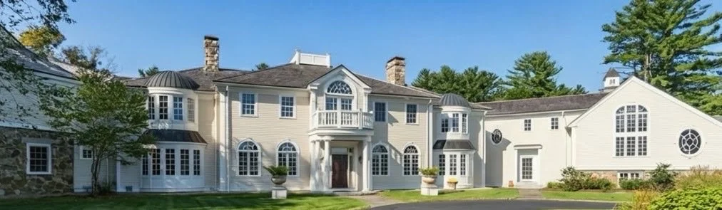 Large white mansion with multiple windows, a small balcony