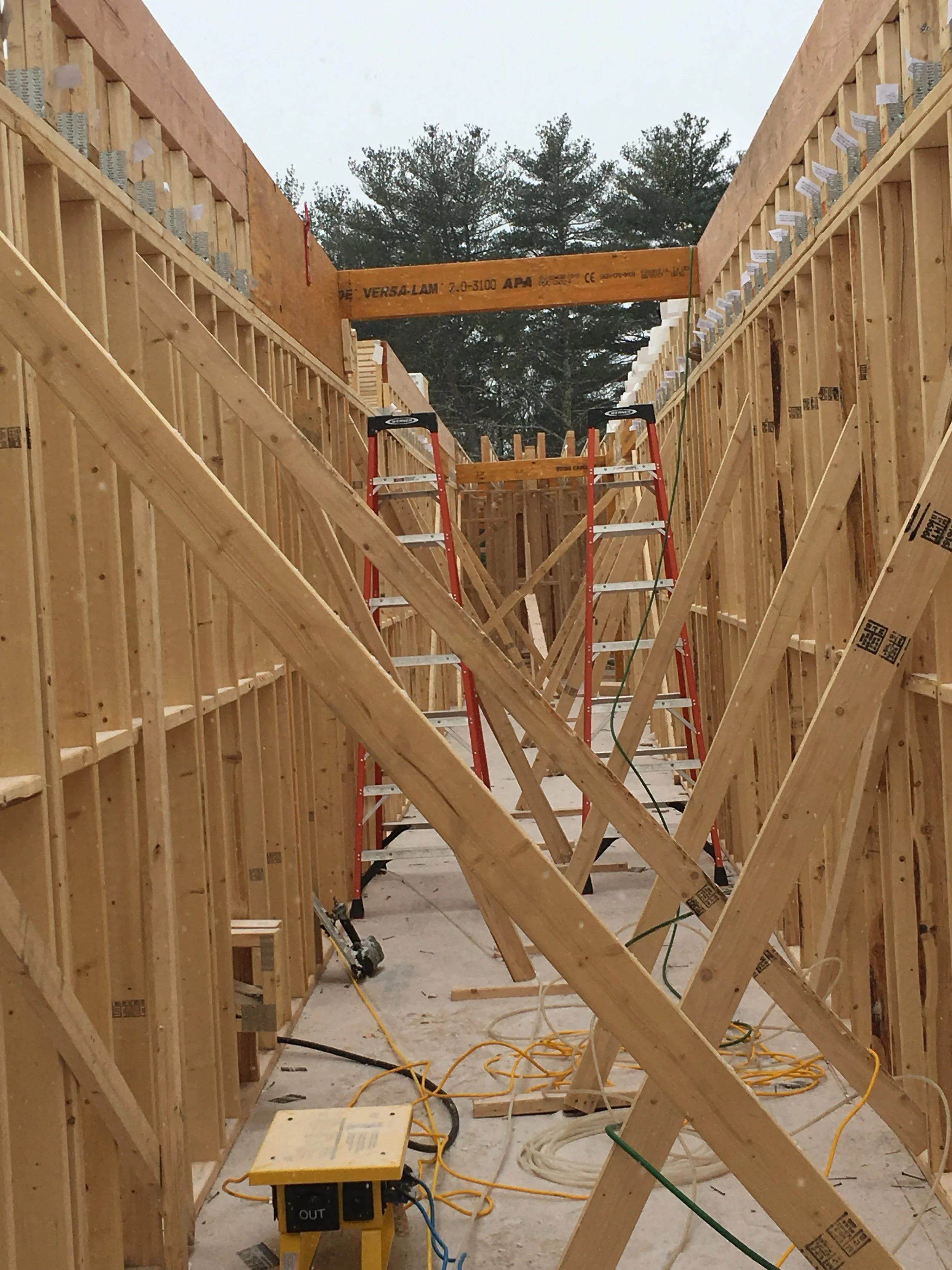 View of a construction site with wooden framing, ladders, and construction tools.