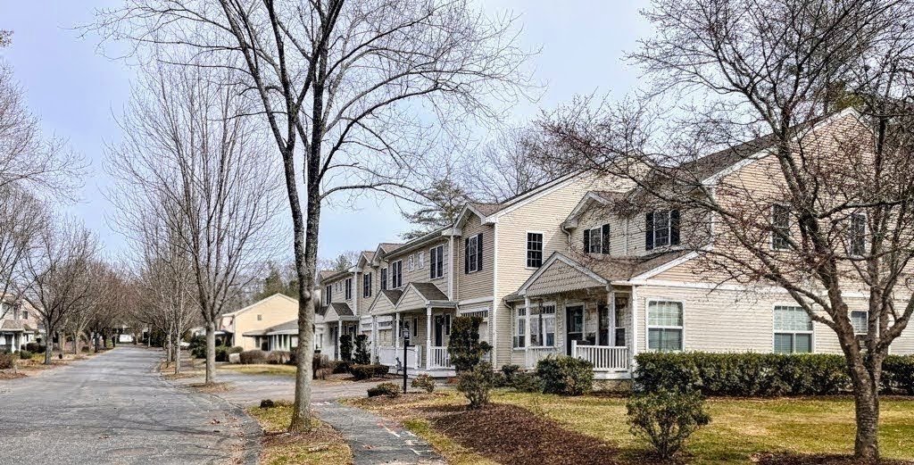 A suburban neighborhood street with multi-story townhouses,