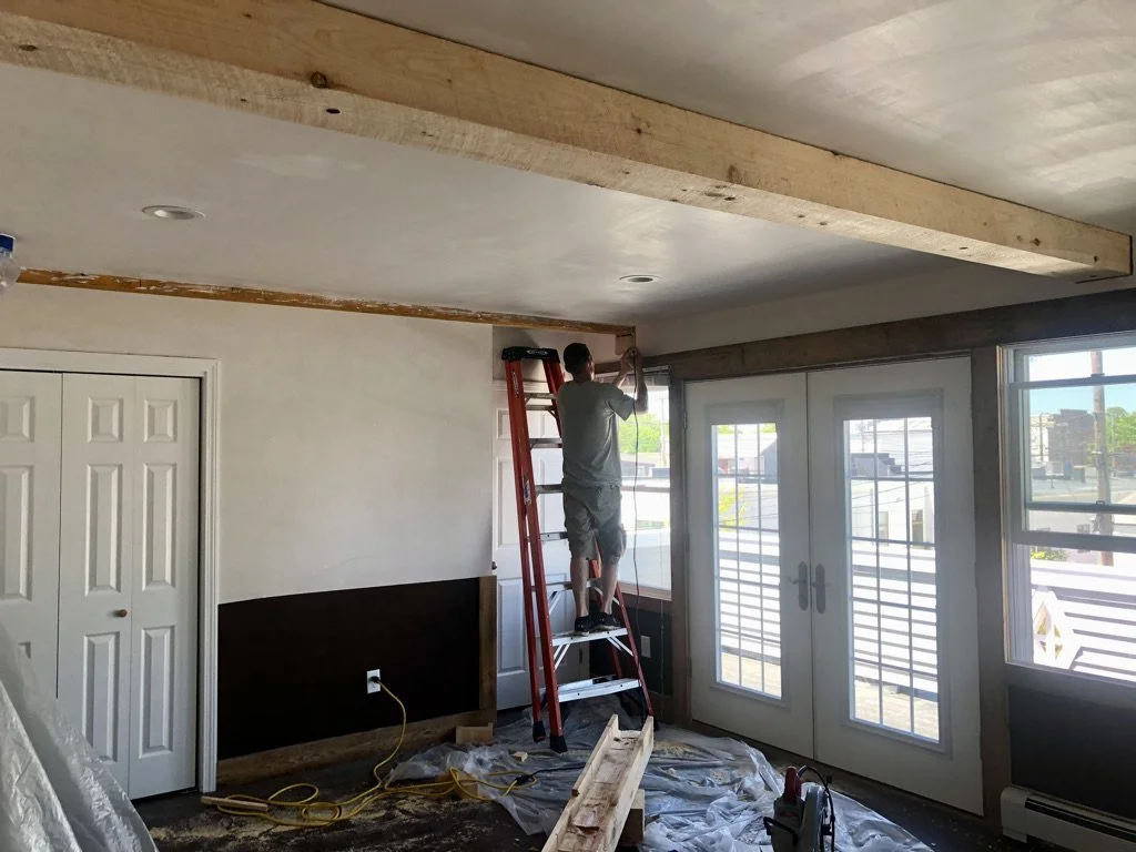  a wooden beam on a ceiling in a room with large windows and a sliding glass door.