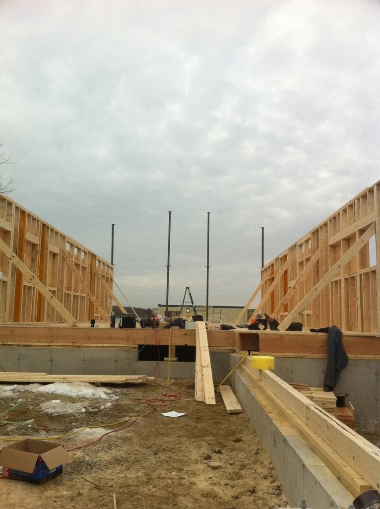 Construction site with wooden framing for a building, overcast sky, construction tools and materials on site.