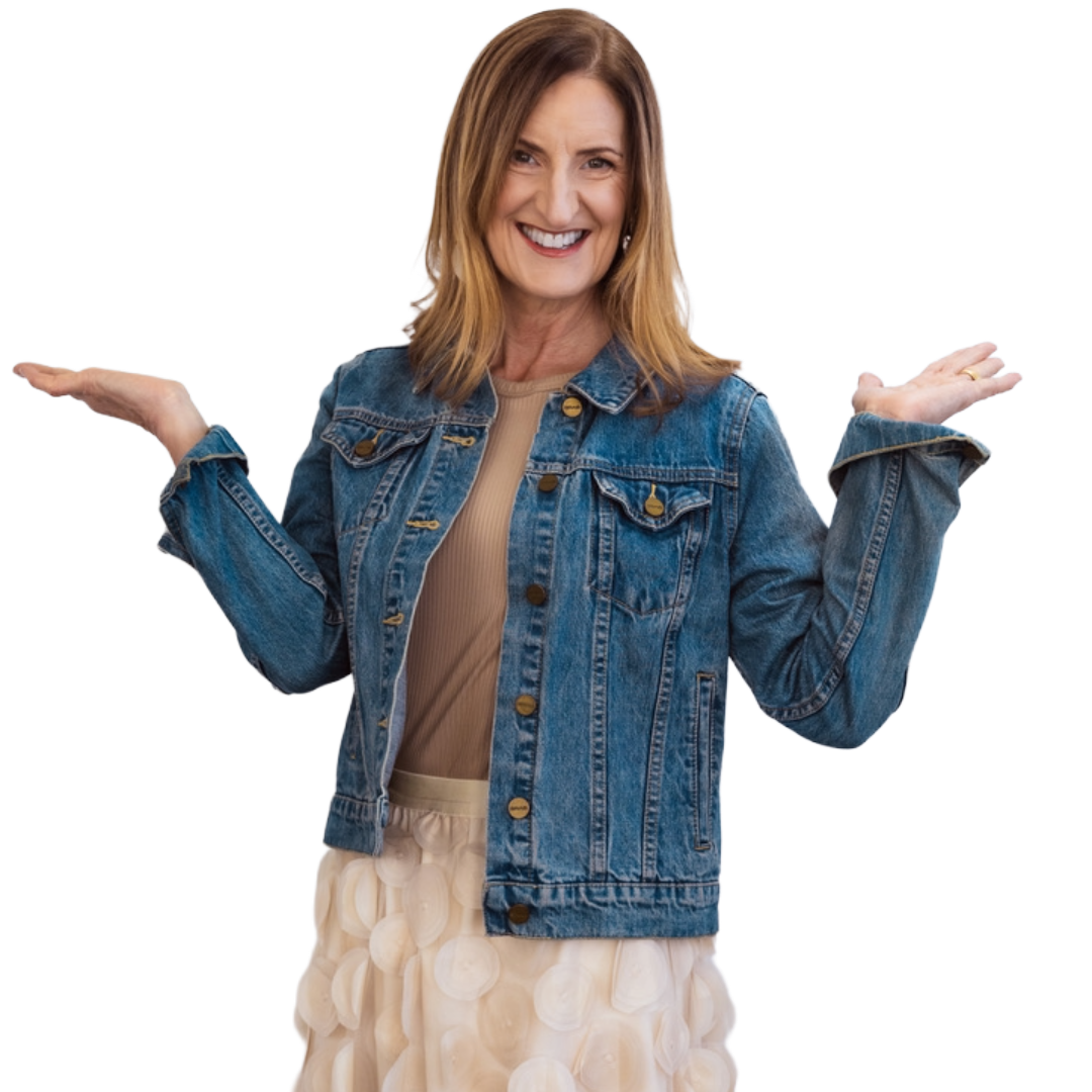 Woman with shoulder-length light brown hair smiling and shrugging, wearing a denim jacket over a tan top, and a cream-colored skirt with textured circles.