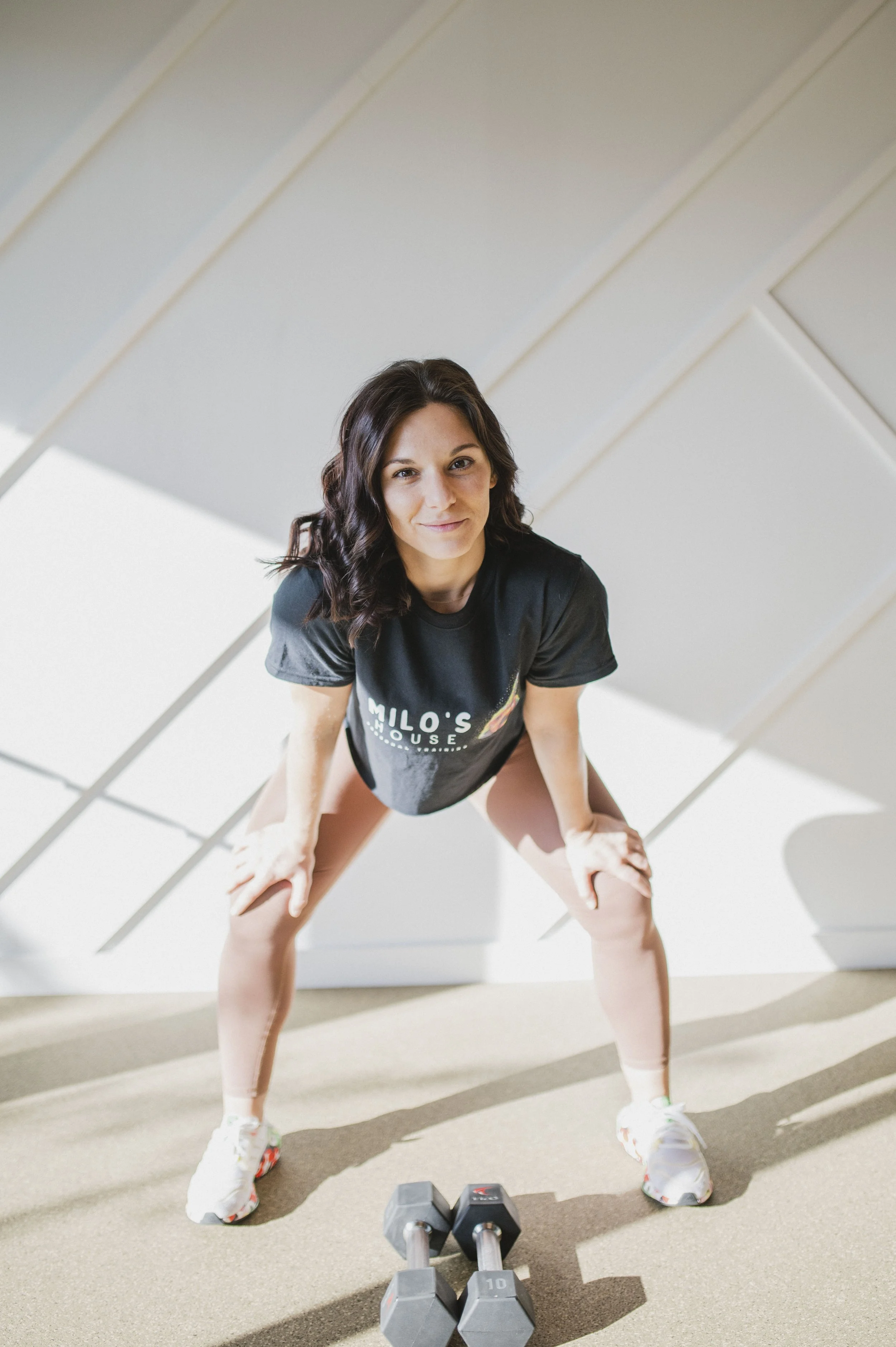 Female personal trainer at Milo’s House in West Palm Beach demonstrating a strength training movement in a boutique fitness studio