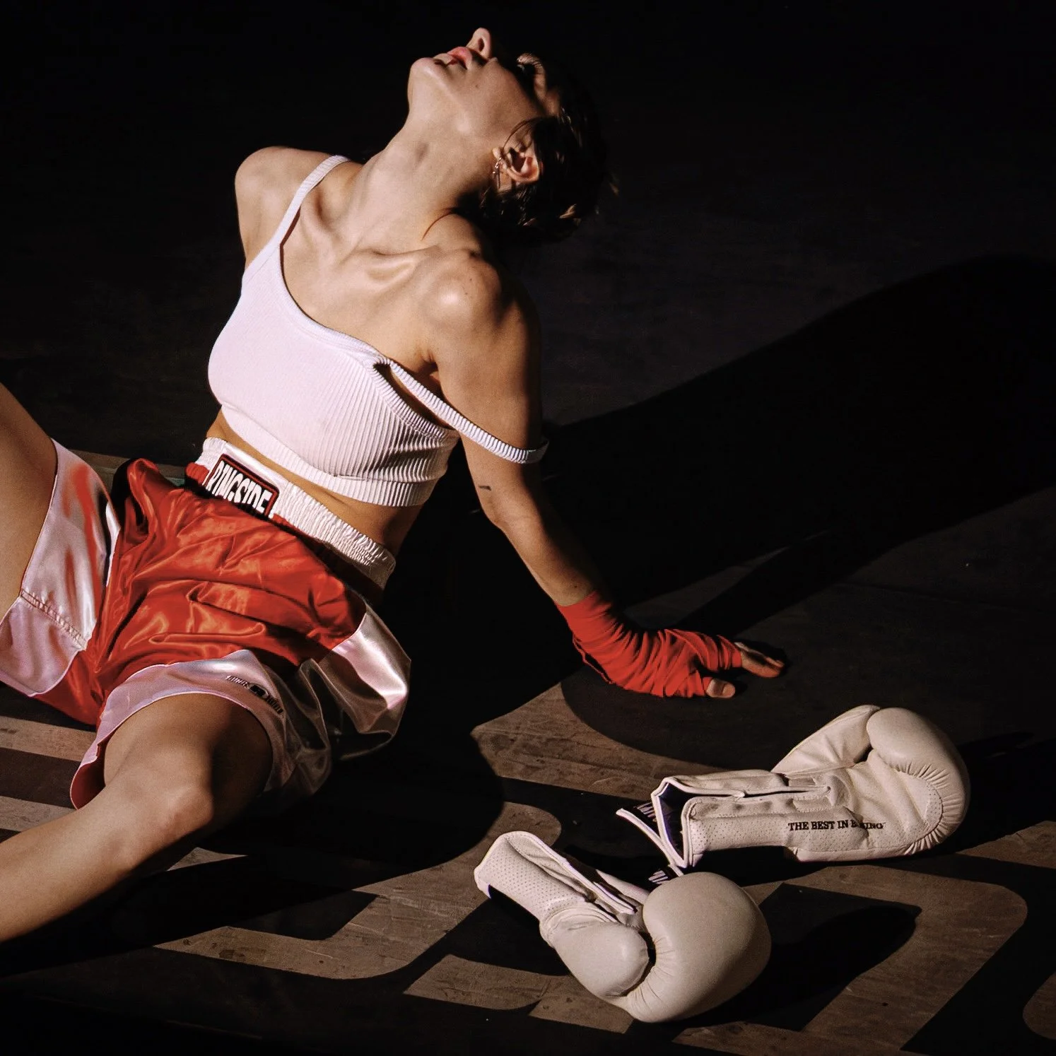 need to know Single Artwork shot by Chinaza Ajuonuma. Taylor Pearlstein sits on the ground in a boxing ring, wearing red boxing shorts, red wrist wraps, and a white bra. Her head is thrown back and a pair of white boxing gloves rest beside her.