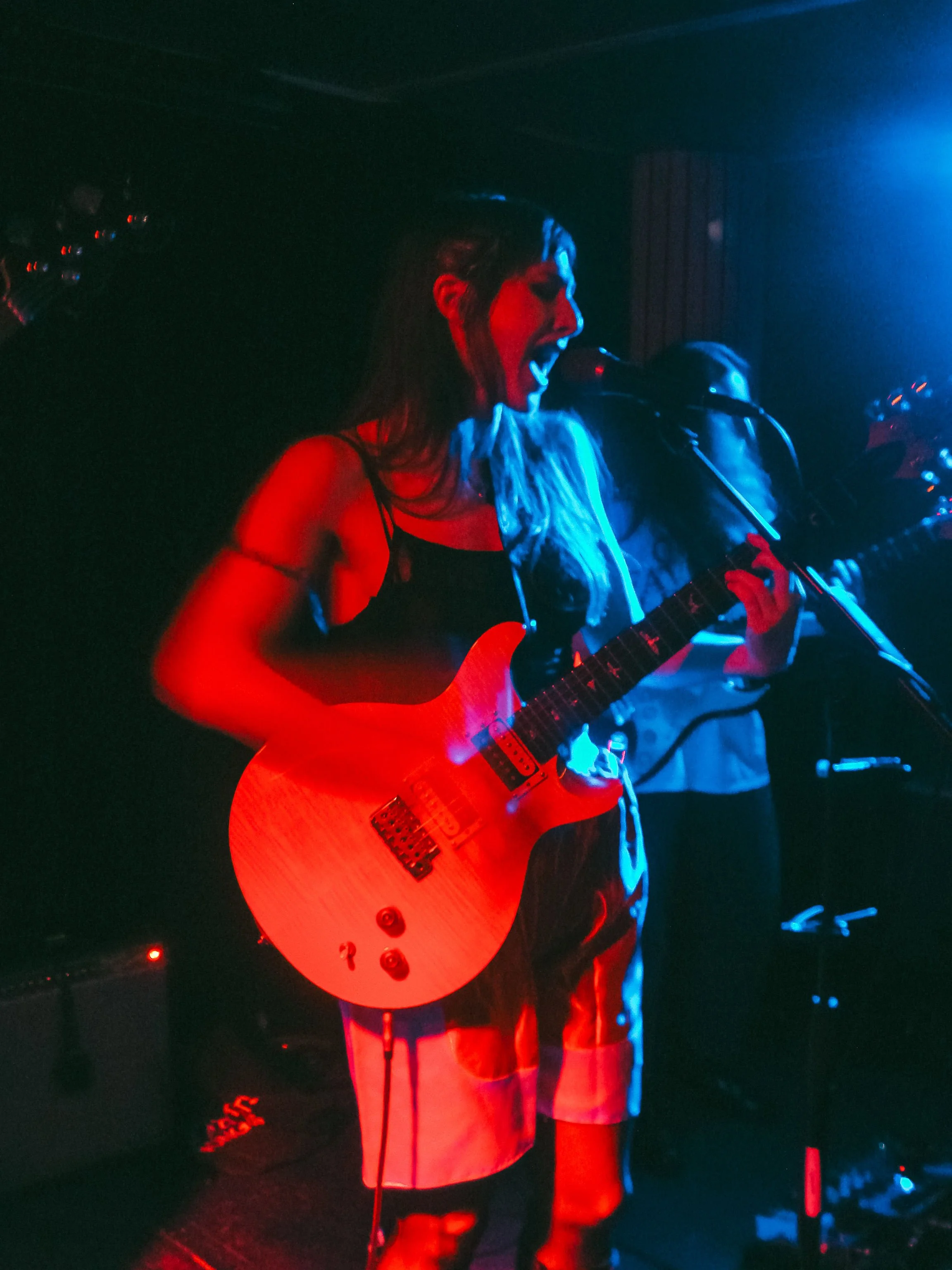 Stupid Lucky Live at Cassette in Ridgewood Queens, NYC - Photo by Beth Crane on Digital Camera. Taylor Pearlstein sings at the mic, her yellow PRS guitar in front of her.