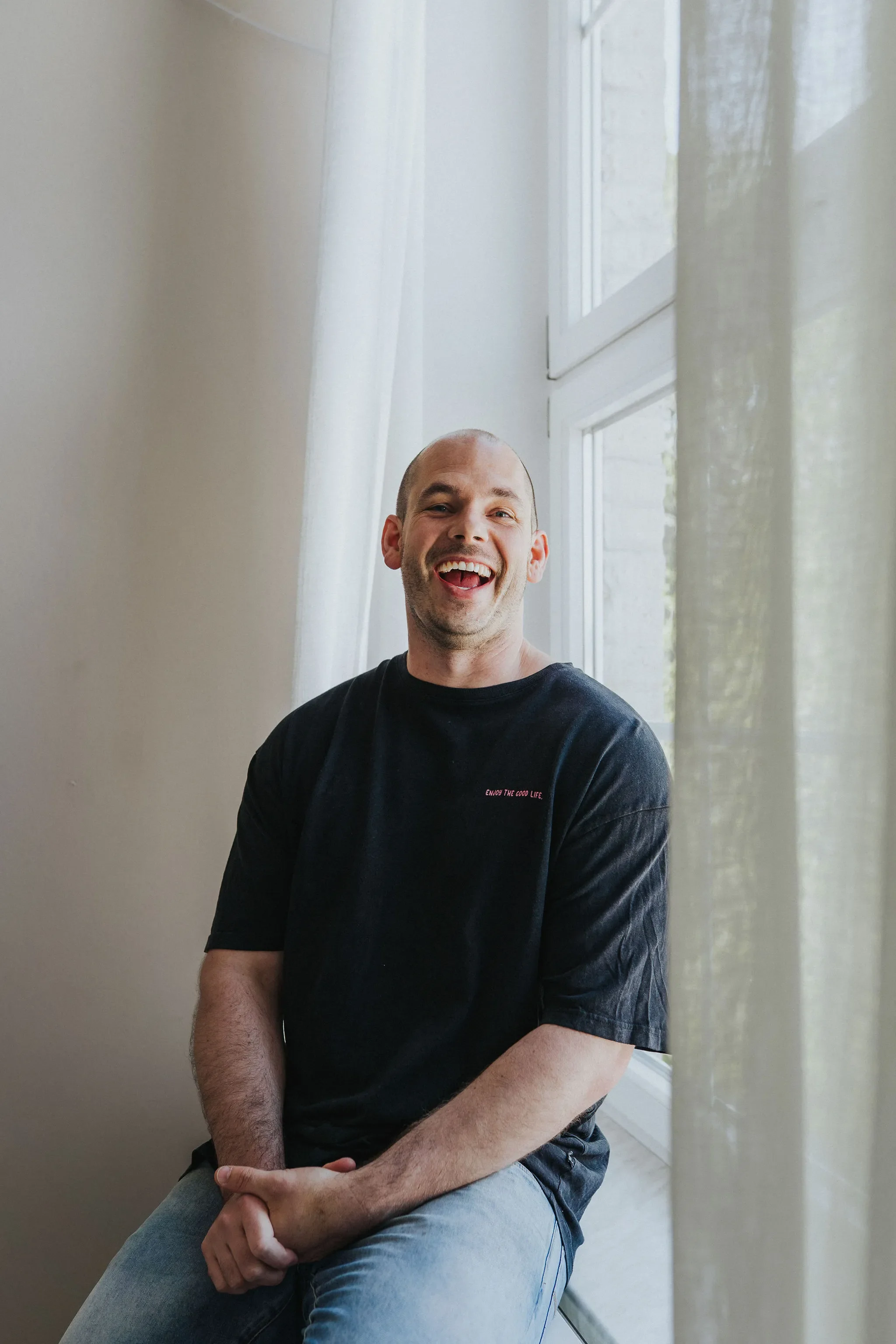 Tim Schröder sitting on a windowsill, sunlight on his face