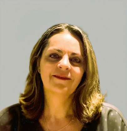 A woman with shoulder-length brown hair and light skin, smiling slightly, wearing a dark top with a small dot pattern.