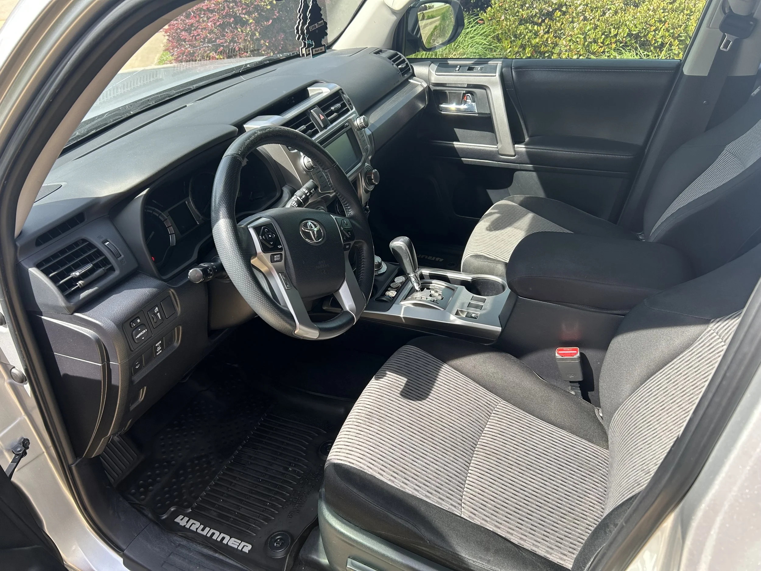 Interior of a Toyota 4Runner with gray and black seats, steering wheel, gear shift, and dashboard, showing the front passenger and driver seats.