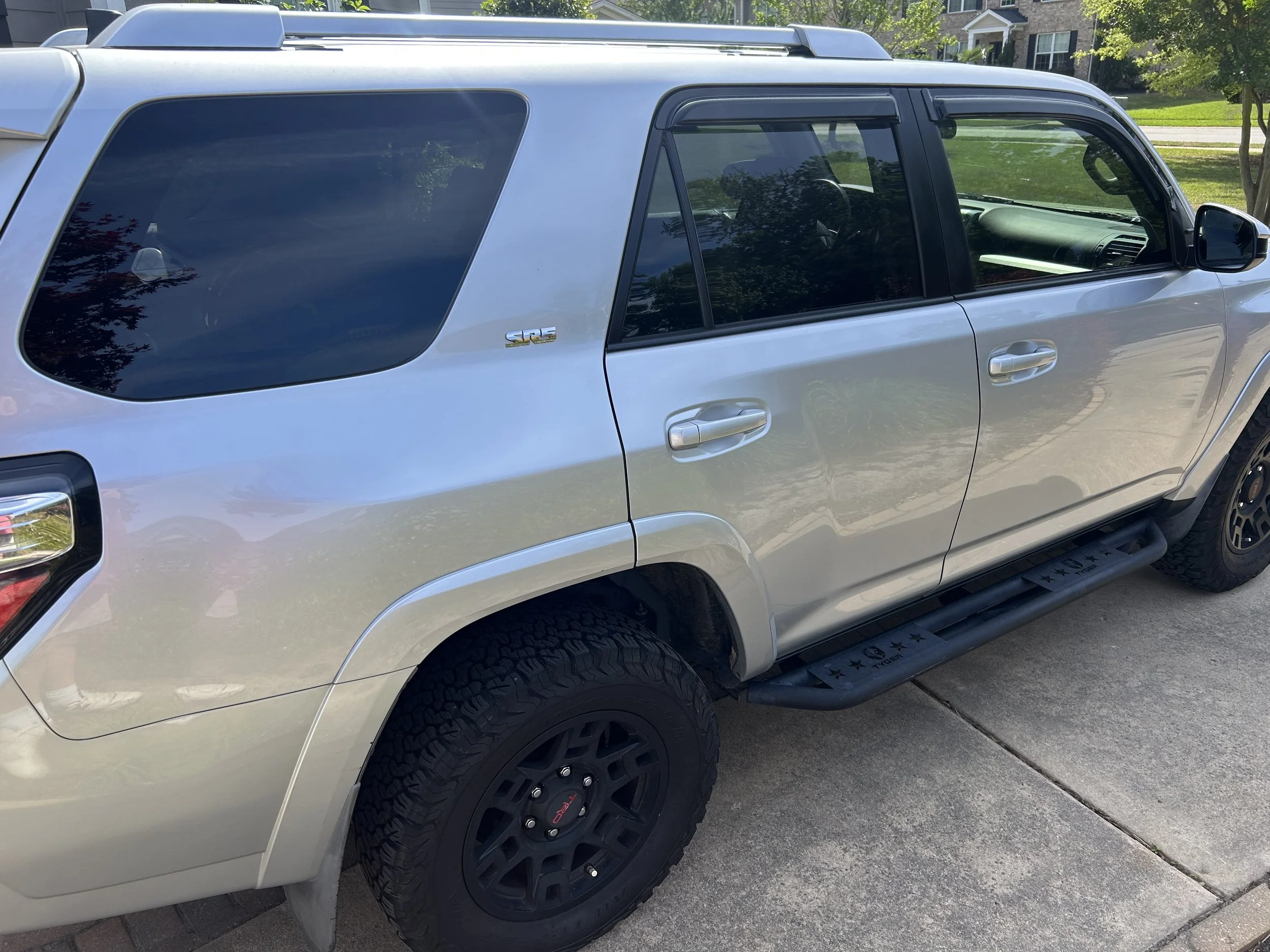 Silver Toyota 4Runner parked on a driveway with trees and houses in the background.