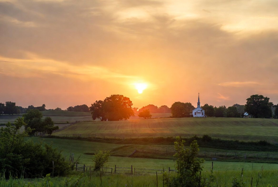 Sunset over a rural landscape with a church and trees