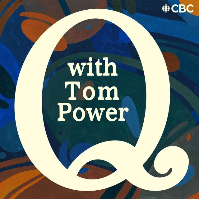 Illustration of a large, white letter 'Q' with the text 'with Tom Power' inside, over a colorful, abstract background with swirling patterns and splashes of blue, green, and orange.