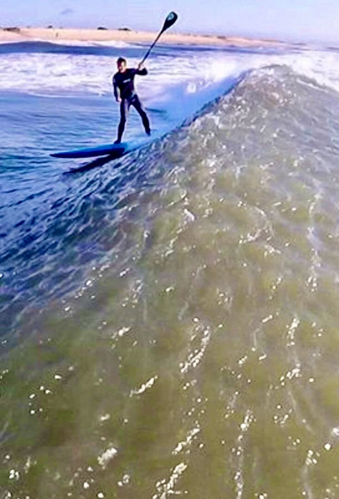 Person in wetsuit surfing on a wave in the ocean.