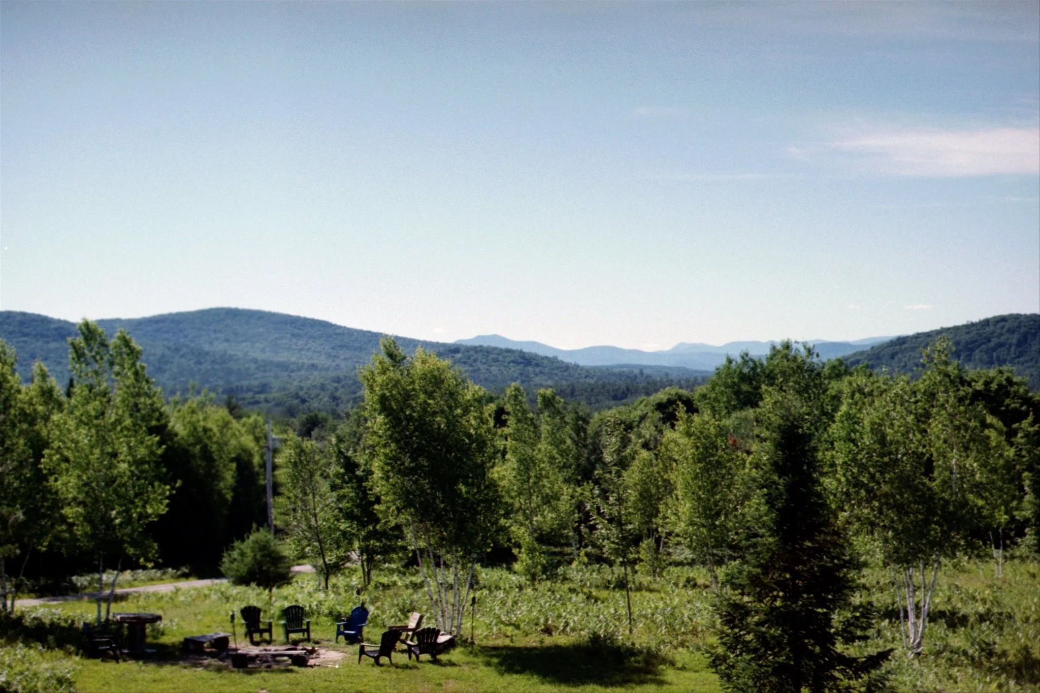 A scenic view of green trees, rolling hills in the distance, and a clear sky.
