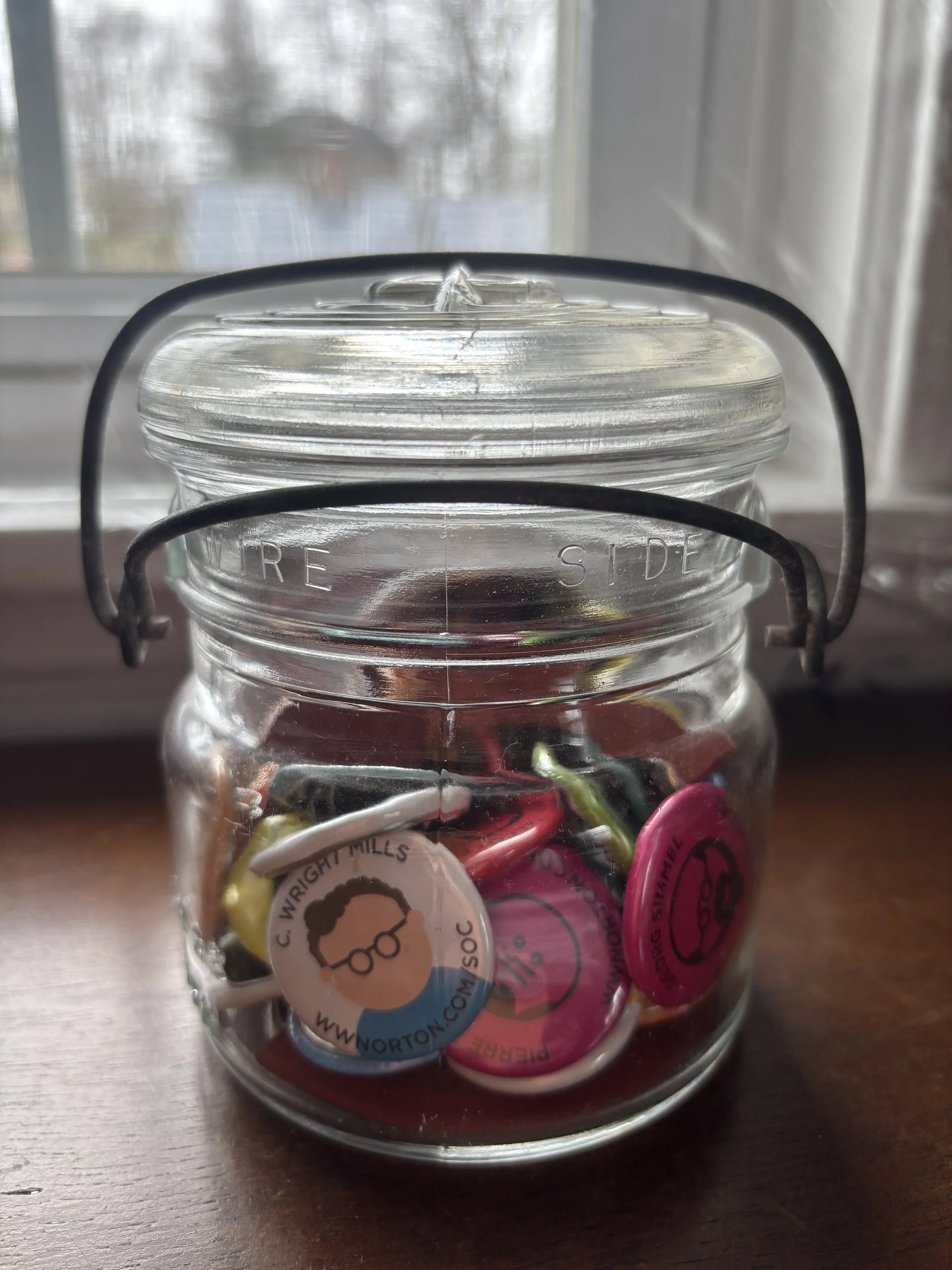 An old jar full of W. W. Norton Publisher's sociologist buttons.
