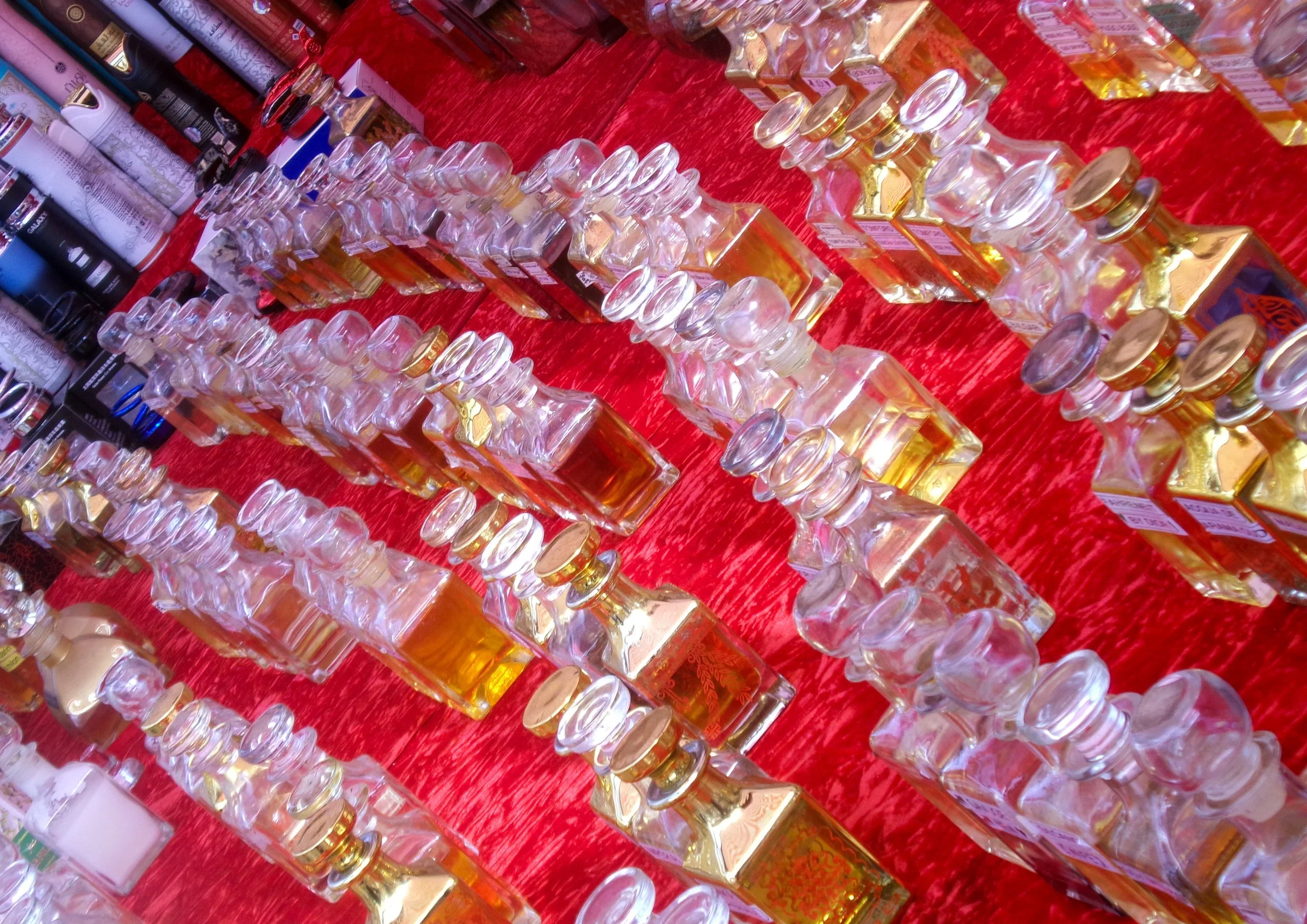 Rows of perfume bottles on a red tablecloth at a market or store display.