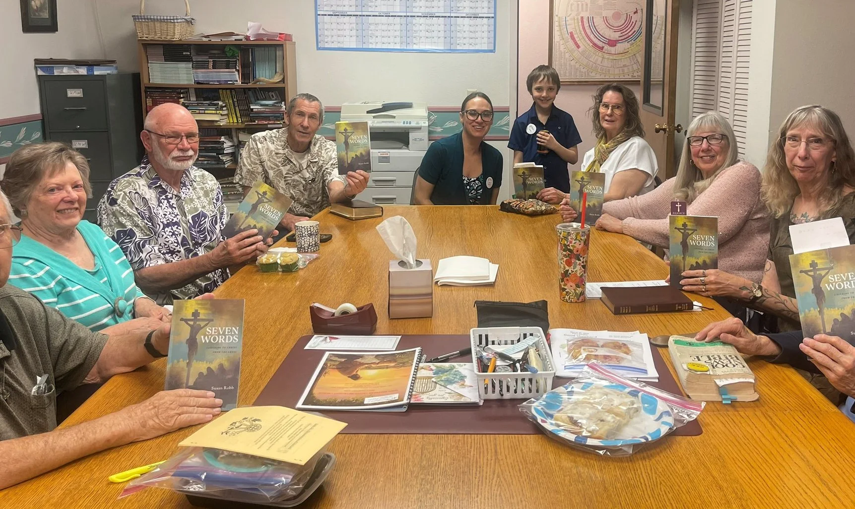 Adults Insights Sunday School group sitting around a conference table, holding copies of a book titled "Seven Words" by Susan Robb, participating in a meeting and book discussion.