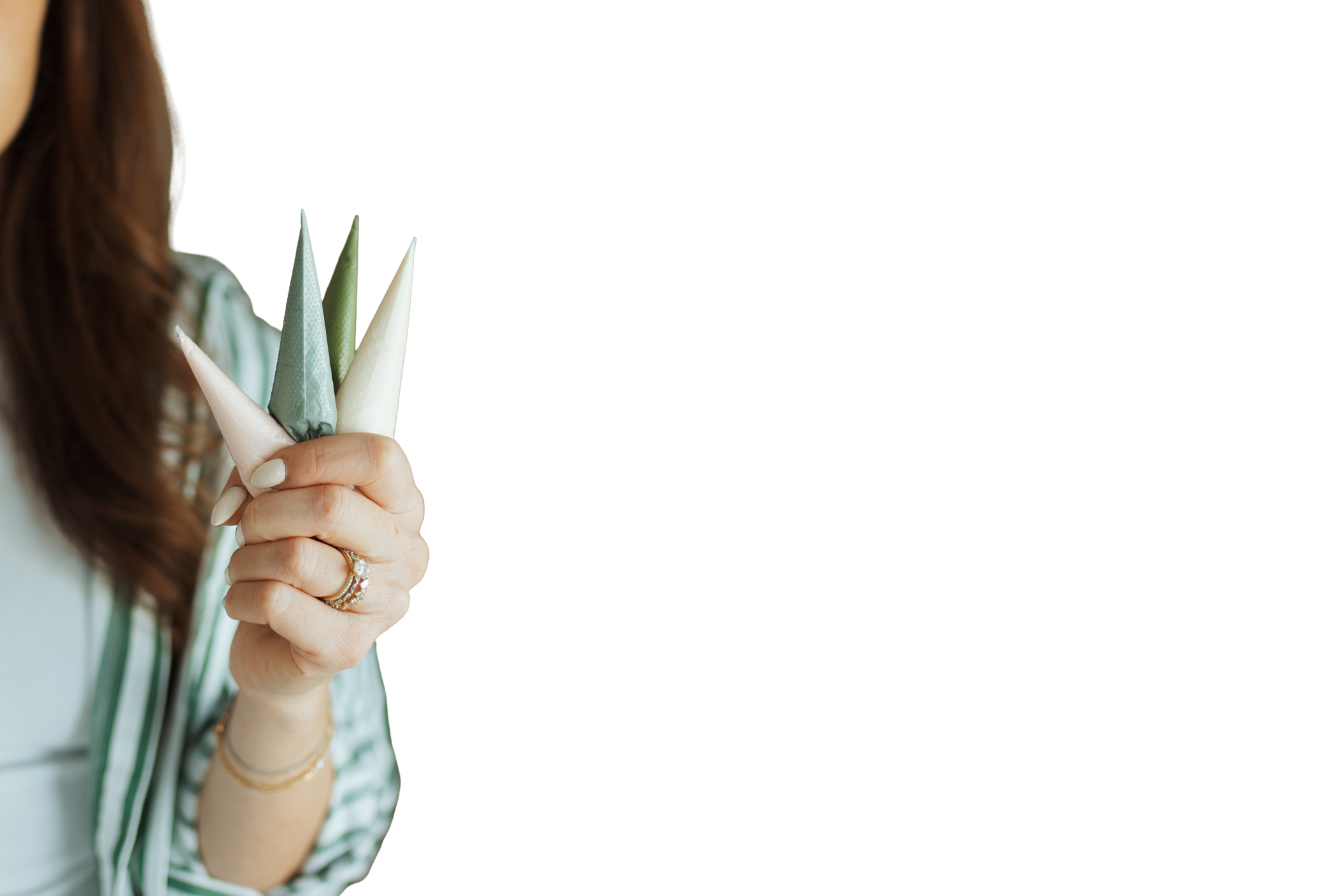 Close-up of a woman holding pastel-colored napkins folded into cones against a black background.