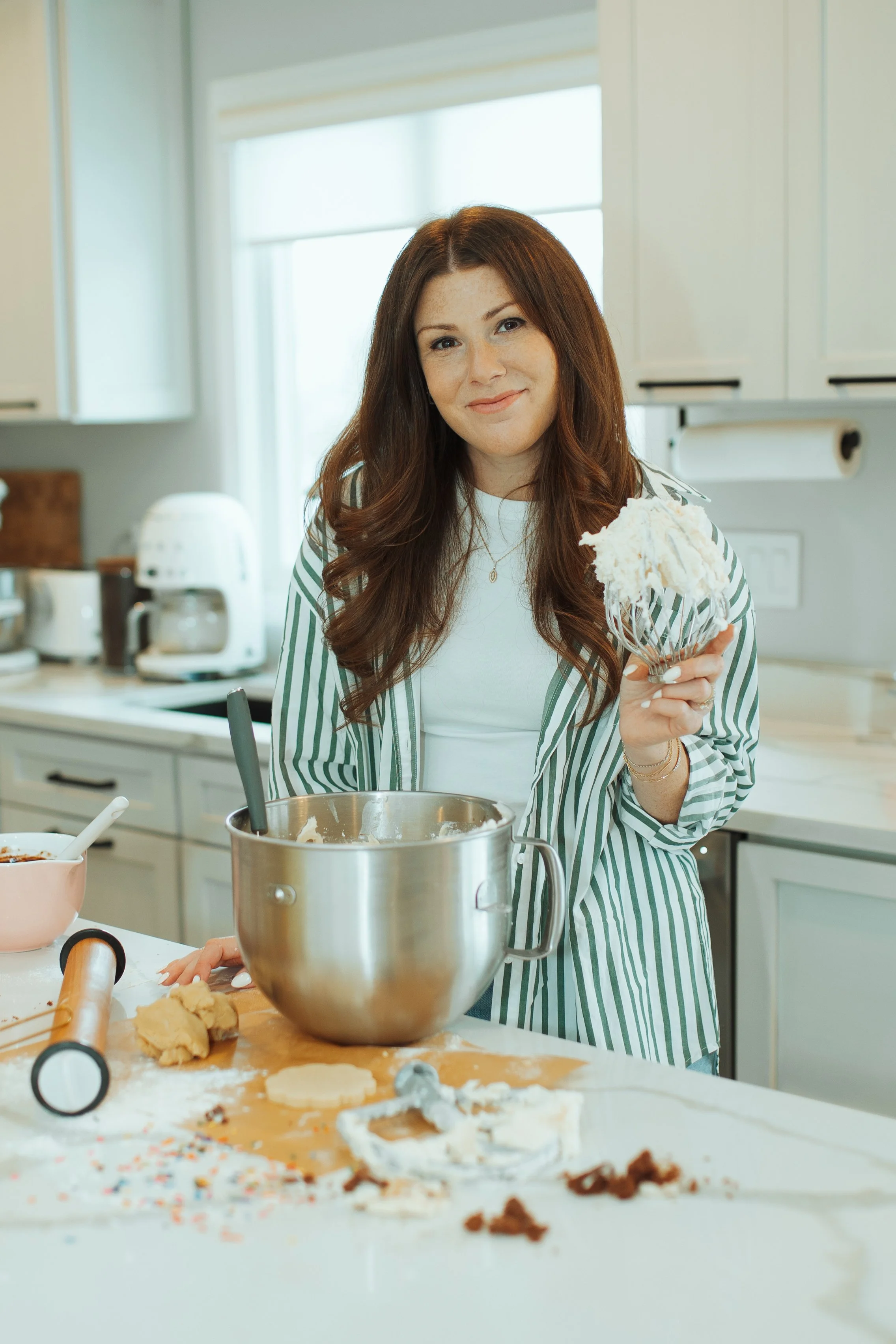 Woman in a kitchen holding a bowl of whipped cream or frosting.