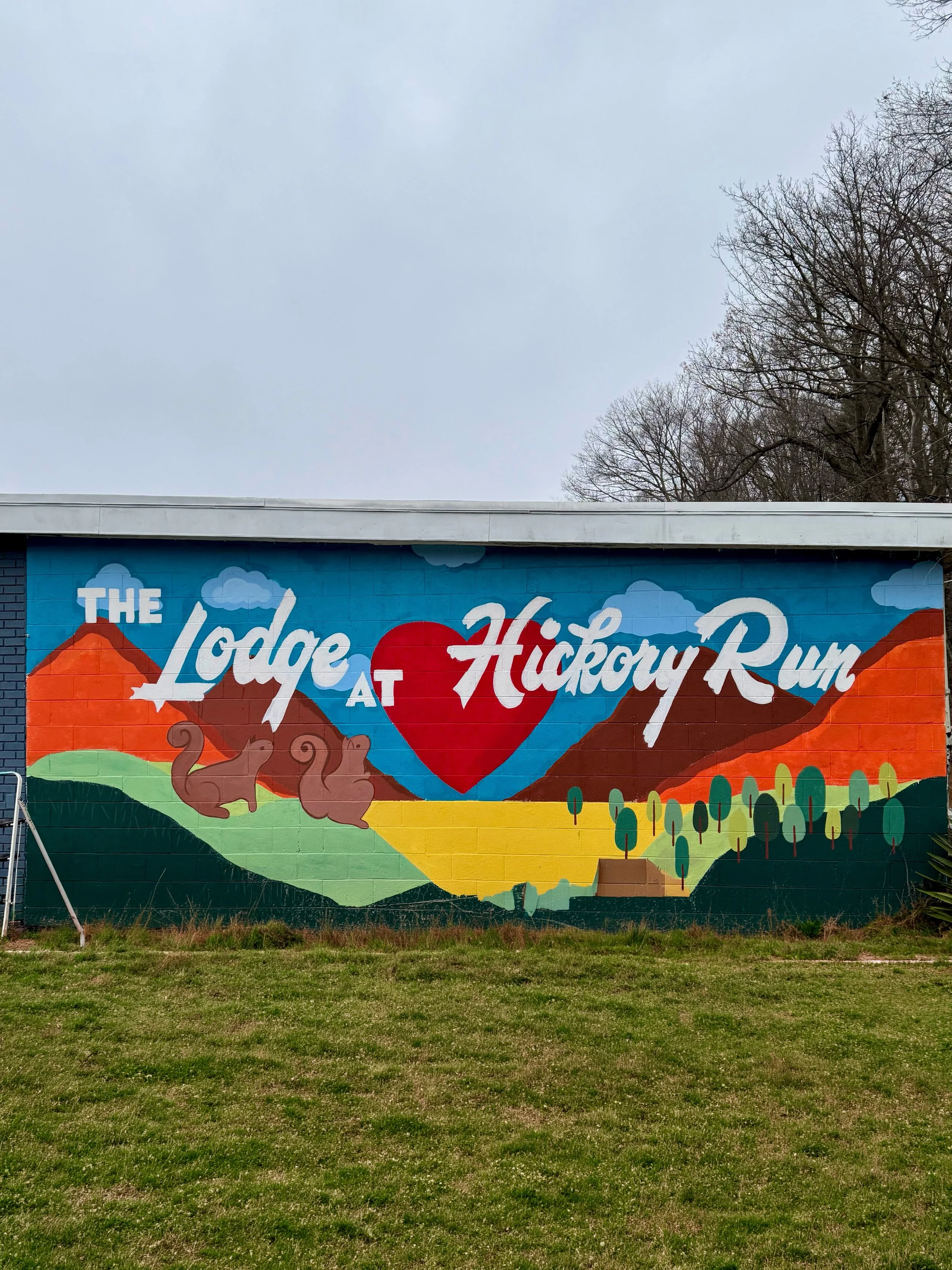 Colorful mural on a building wall with the words "The Lodge at Hickory Run" and a depiction of a mountain landscape with trees and a red heart in the center.