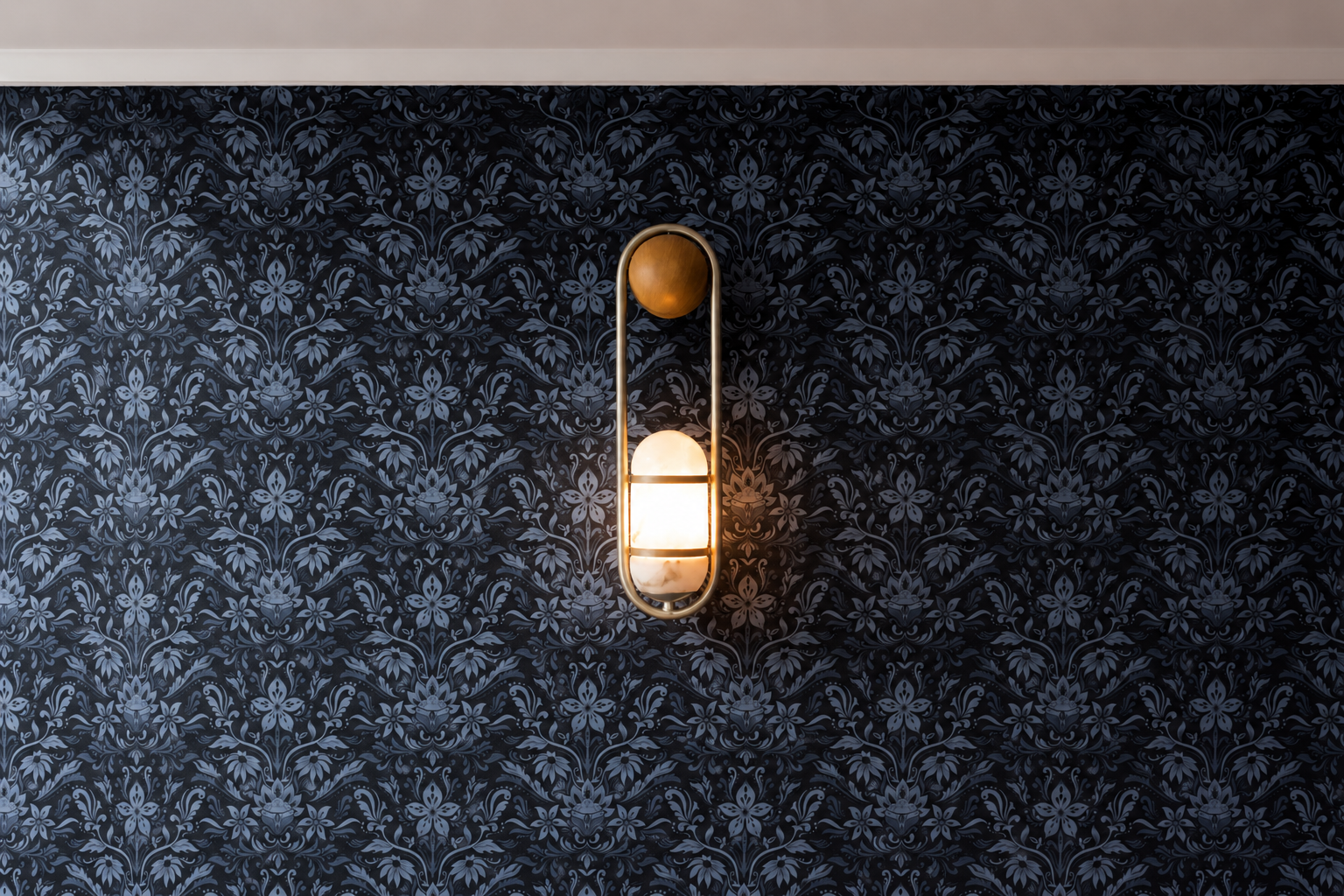 Wall-mounted light fixture with a glowing white semi-sphere and a round wooden top, installed on a black wallpapered wall with a floral pattern.