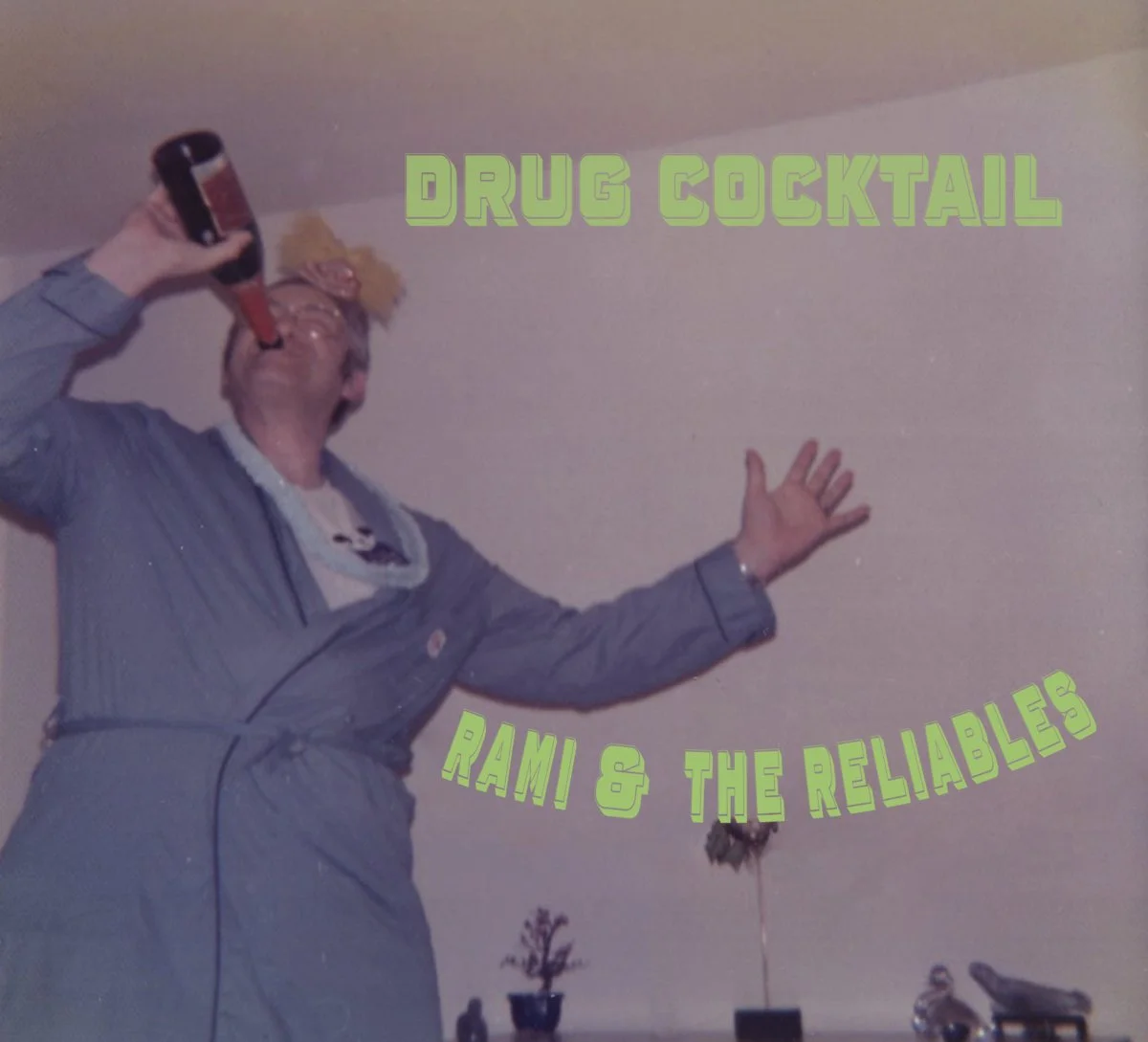 Album cover for 'Drug Cocktail' by Rami & the Reliables (2023). Photo by Chris Ligon. A man wearing a bathrobe chugging from a large bottle, having a bash.