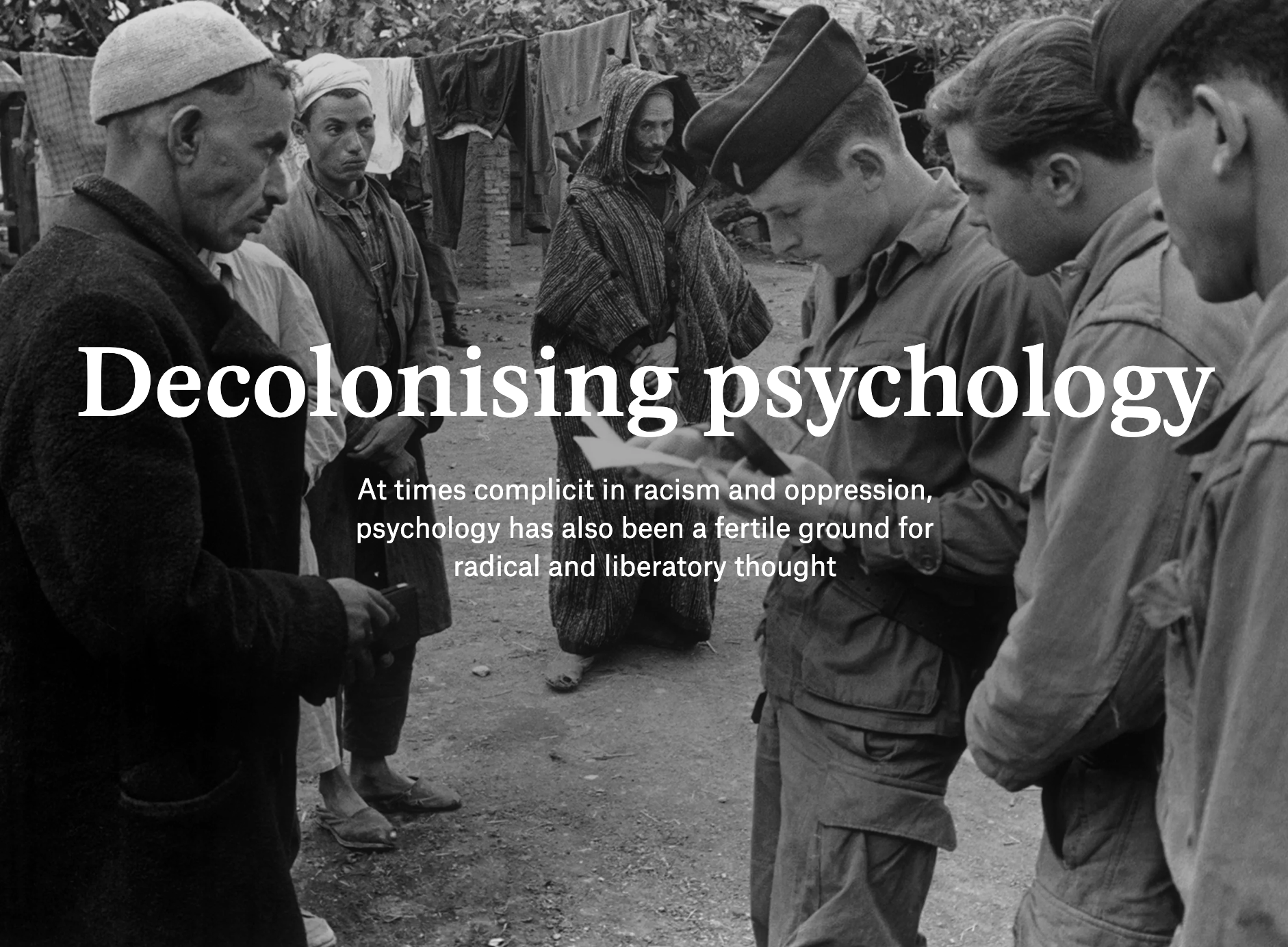 Black-and-white photo showing a group of people, some in military uniforms, with a woman kneeling in the background. Overlaid text reads 'Decolonising psychology' and 'At times complicit in racism and oppression, psychology has also been a fertile ground for radical and liberatory thought.'
