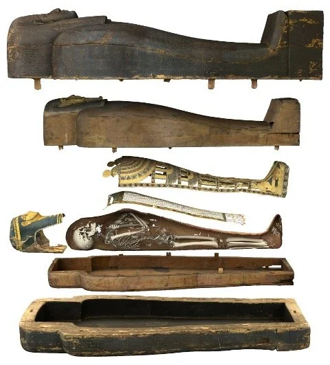 A collection of ancient wooden and decorative artifacts, including carved wooden objects, a decorated tube, a metallic statue, and carved wooden boxes.